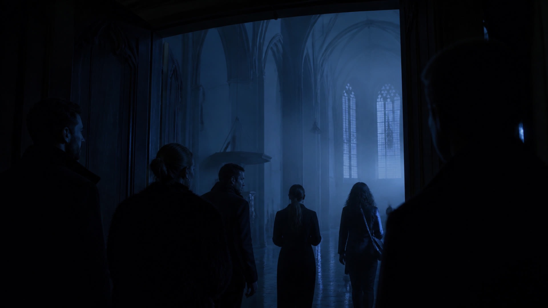 Arrival into a frozen room: silhouettes entering a cold blue haze.