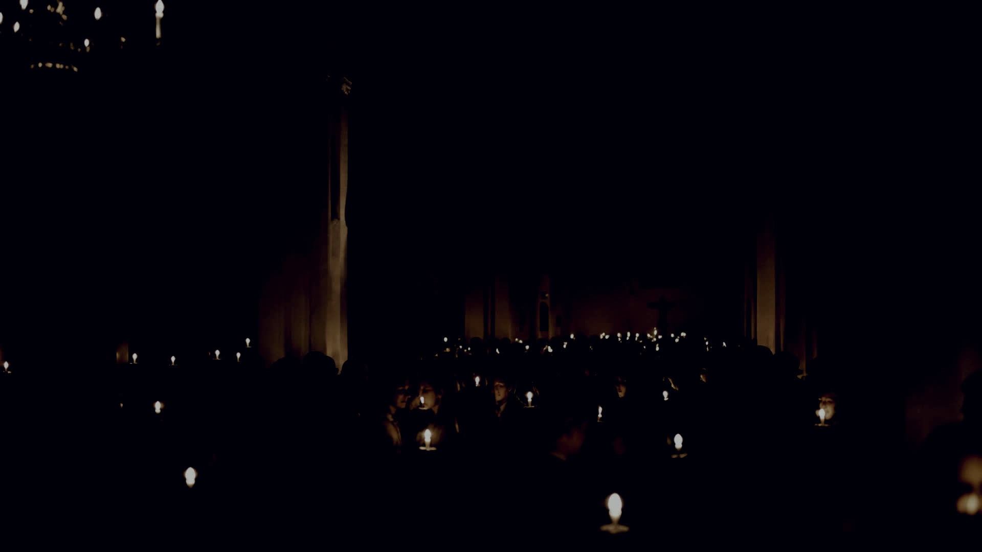 The church almost entirely dark, its shape described only by hundreds of small points of light at head height.