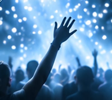 A raised hand above the crowd in falling light.